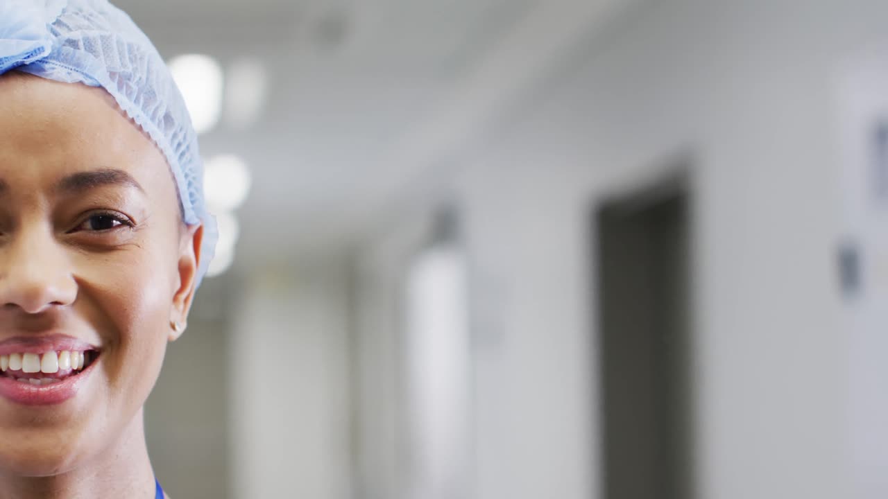 el retrato de la mitad de la cara de una mujer médica bi-racial sonriente en el sombrero, en el pasillo, en el espacio de copia.