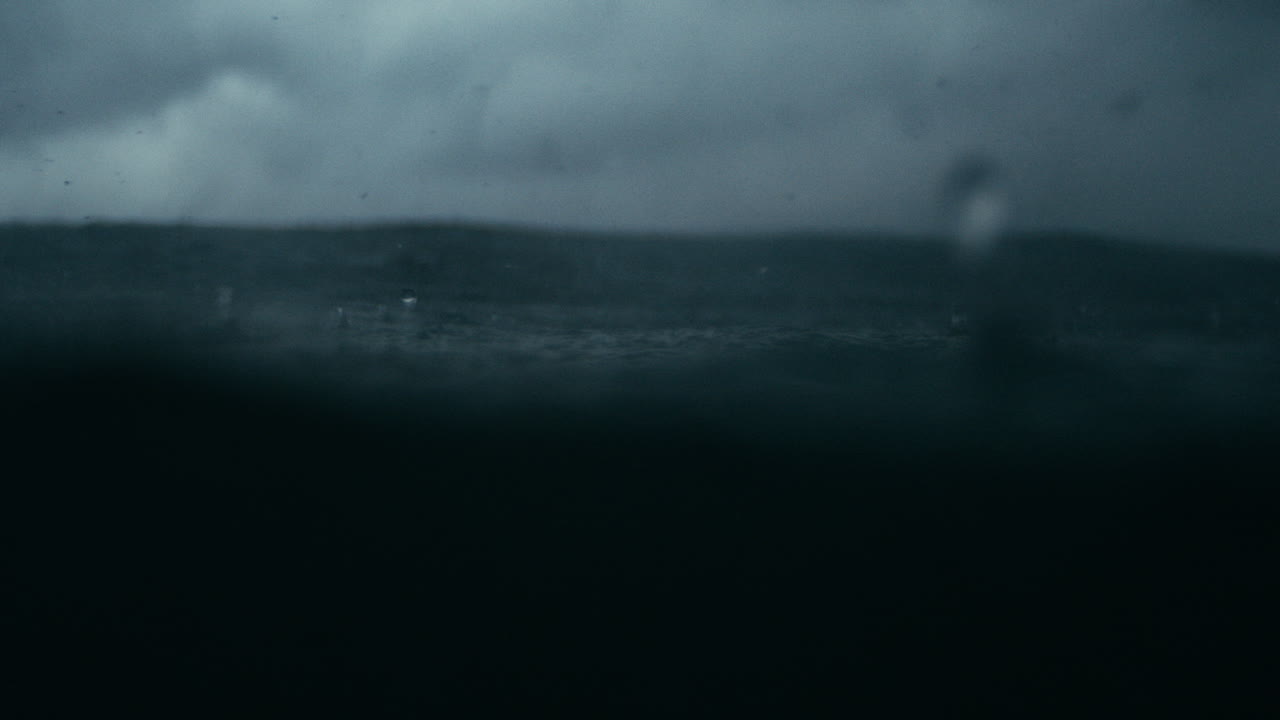 Raindrops falling in super slow motion on ocean under dramatic clouds