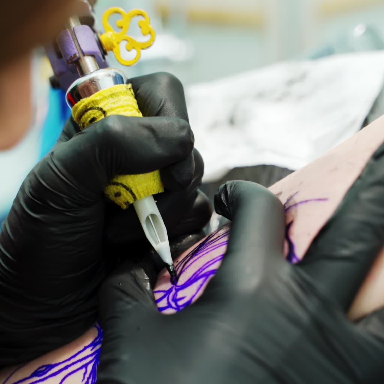Artist of tattoos at work. Tattooist wearing black latex gloves applies the ink on the picture on customer's hand