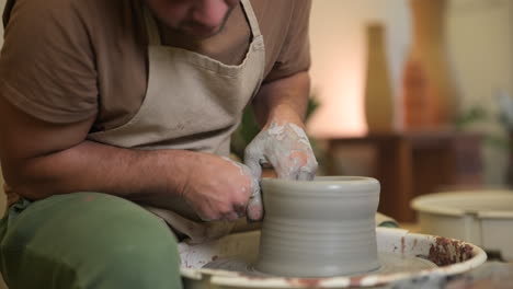 Male-artisan-craftsman-slow-motion-forming-clay-vase-sculpture-on-workshop-pottery-wheel