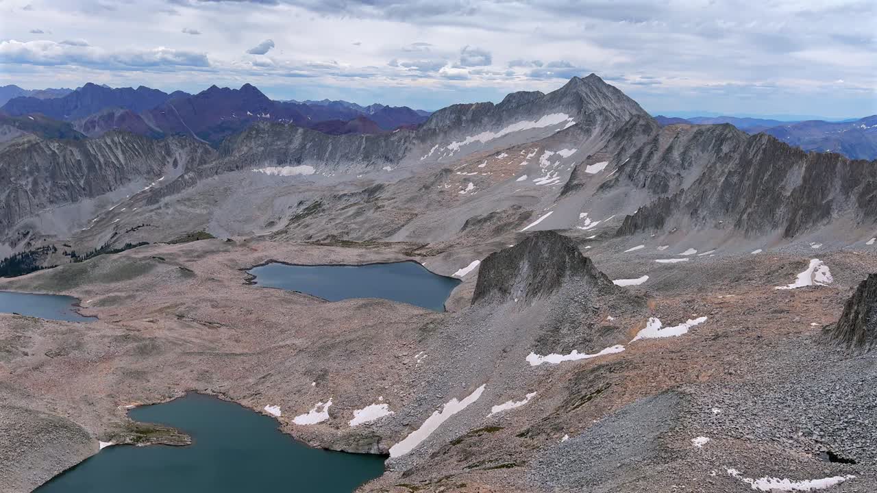 Capitol Peak 14er Wilderness high alpine elevation Rocky Mountains Colorado aerial drone Maroon Bells Peaks Mount Snowmass Pierre Lakes summer morning clear blue sky clouds Knifes Edge Ridge pan left