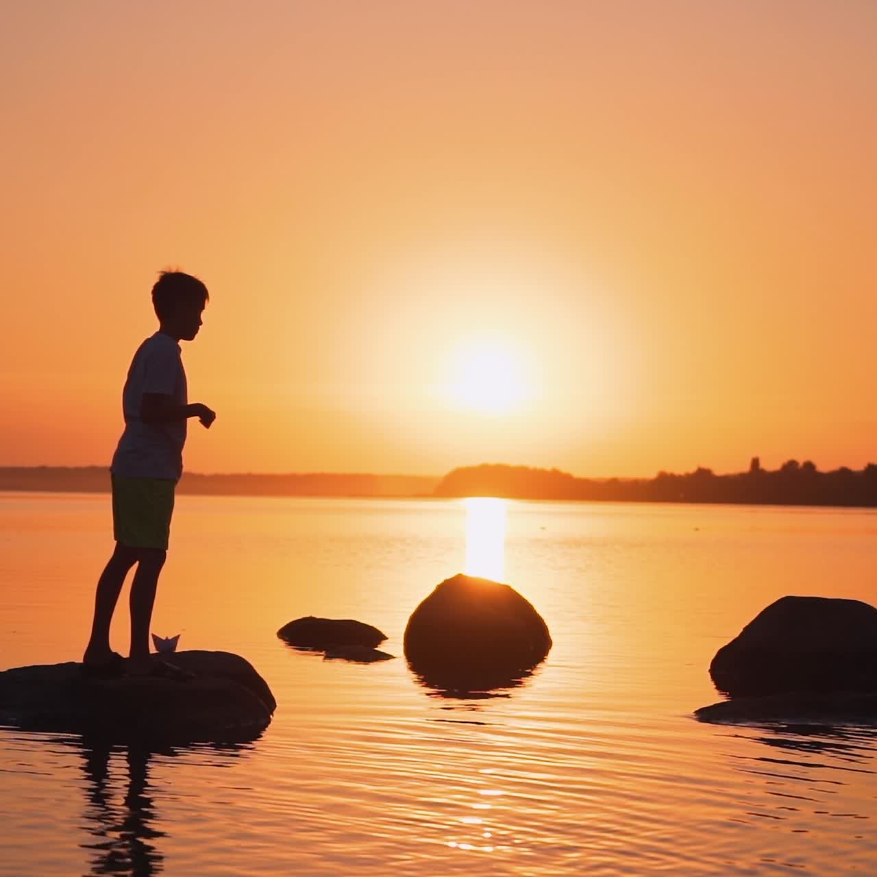 Little boy with paper plane. Beautiful sunset. Origami.