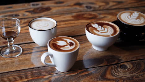 variety of coffee lattes with latte art on a wooden table