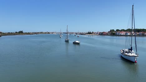 Drone-footage-flying-low-over-the-water-among-anchored-sail-yachts-in-Seixal,-south-of-Lisbon