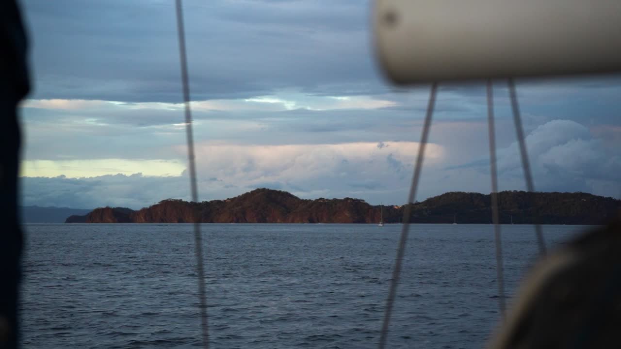 enfoque en la costa tropical rocosa de américa central desde el interior de un barco que está navegando después del atardecer