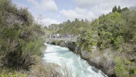 a wide shot of people on the bridge over the huka falls in taupo, nz