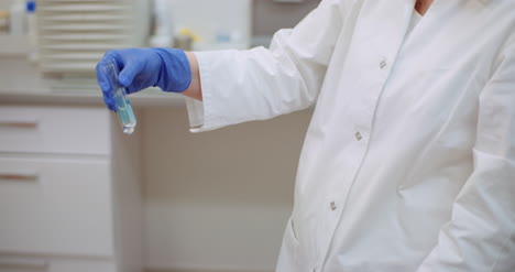 Close-Up-Of-Female-Scientist-Shaking-Test-Tube-In-Laboratory