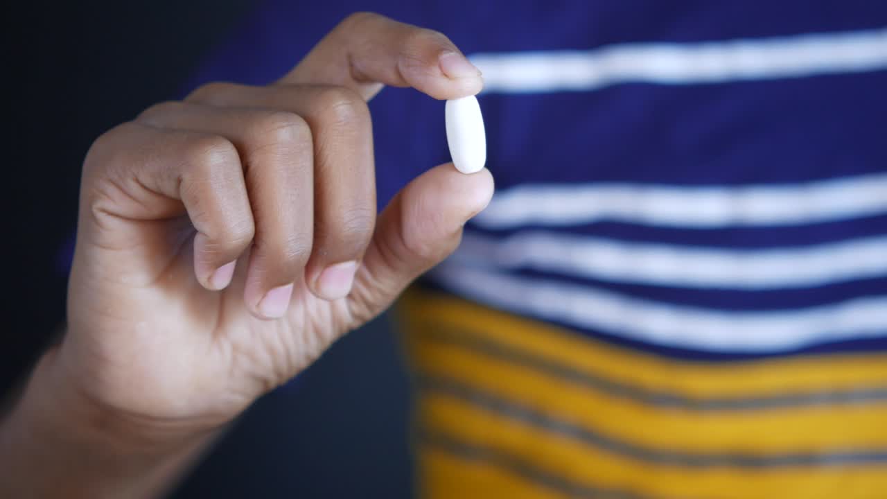 persona que sostiene una píldora blanca