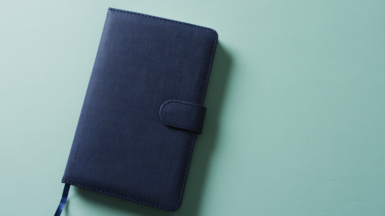 Primo piano di un quaderno blu chiuso con spazio per il testo su sfondo verde al rallentatore