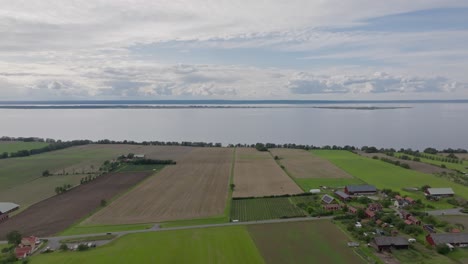 a view of fields and village with lake vattern in the background near brahehus castle in sweden