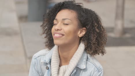 Schönes-Mädchen-Mit-Afro-Haarschnitt,-Das-Auf-Einer-Bank-An-Der-Stadtstraße-Sitzt