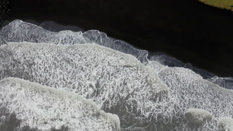 Aerial:-Rising-orbit-shot-of-waves-breaking-on-black-sand-beach-in-Iceland