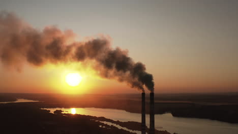 factory pollutes environment at sunset. toxic enterprise chimneys tubing against the evening sky background release black smoke. smoking pipes of harmful manufacture in nature.