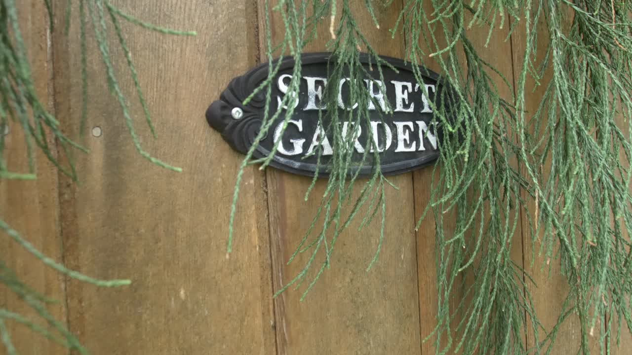 señal de entrada al jardín secreto en la puerta de madera del jardín botánico