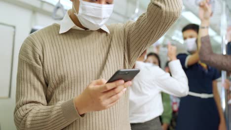 traveler wearing face mask while using mobile phone on public train