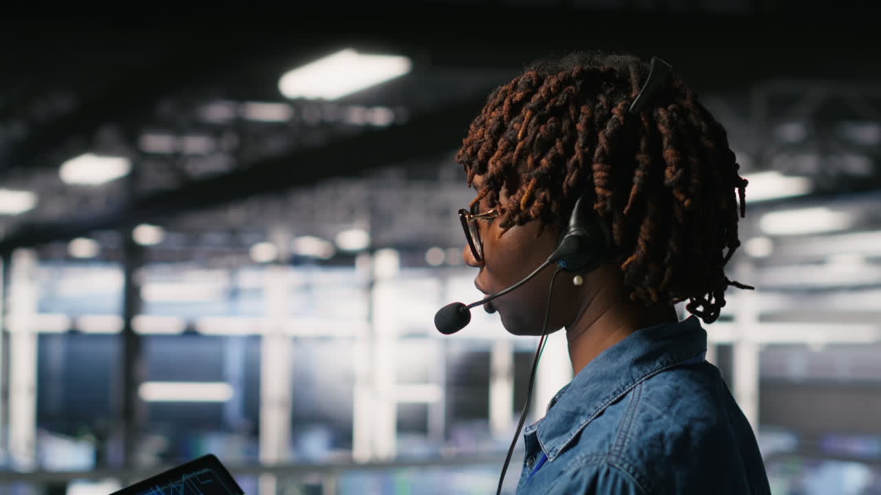 Data center worker speaks in headset mic, overseeing maintenance on AI rigs