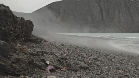 Close-up-slow-motion-shot-of-steam-rising-over-ground-edge-on-desolation-island-with-volcano