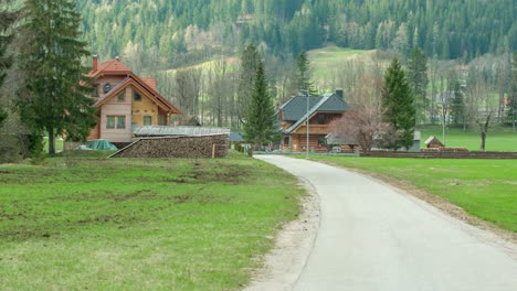 green nature in the valley surrounded with hills and trees and a couple of wooden houses