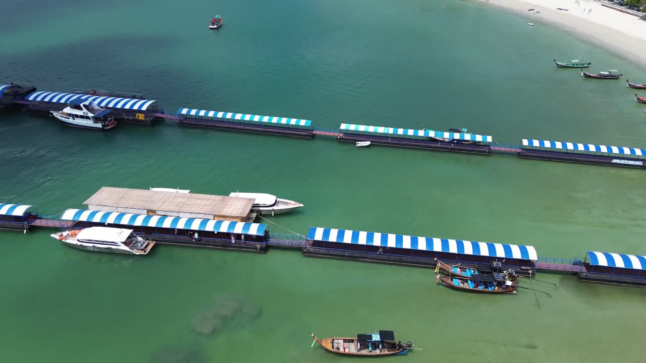 Drone flies behind and reveals the stunning Patong Beach, moving left to right with turquoise water, white sand, and vibrant Phuket coastline under clear skies.