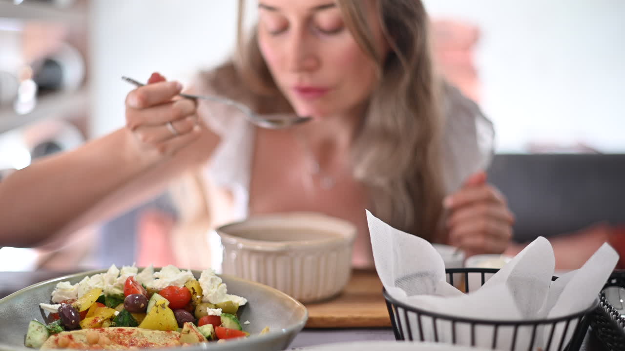 Kvinde i hvid kjole, der spiser suppe på en restaurant