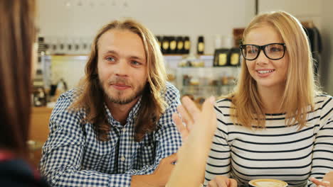 nahaufnahme der gruppe und der multiethnischen gruppe von freunden, die sich unterhalten und lachen, die an einem tisch in einem café sitzen