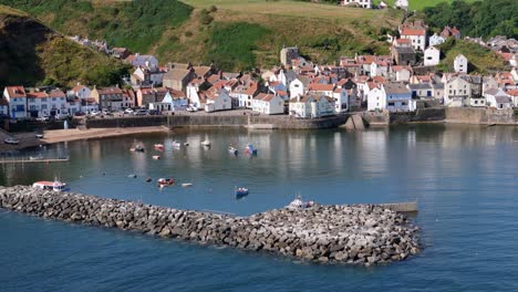 aerial drone view of staithes harbour on the north yorkshire coast with river,houses, boats on a sunny morning in august, summertime