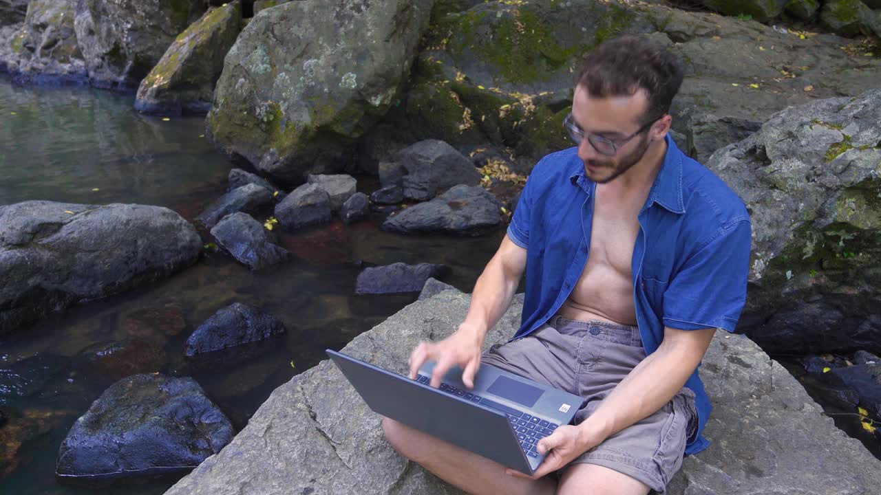joven trabajando con una computadora portátil en la naturaleza.