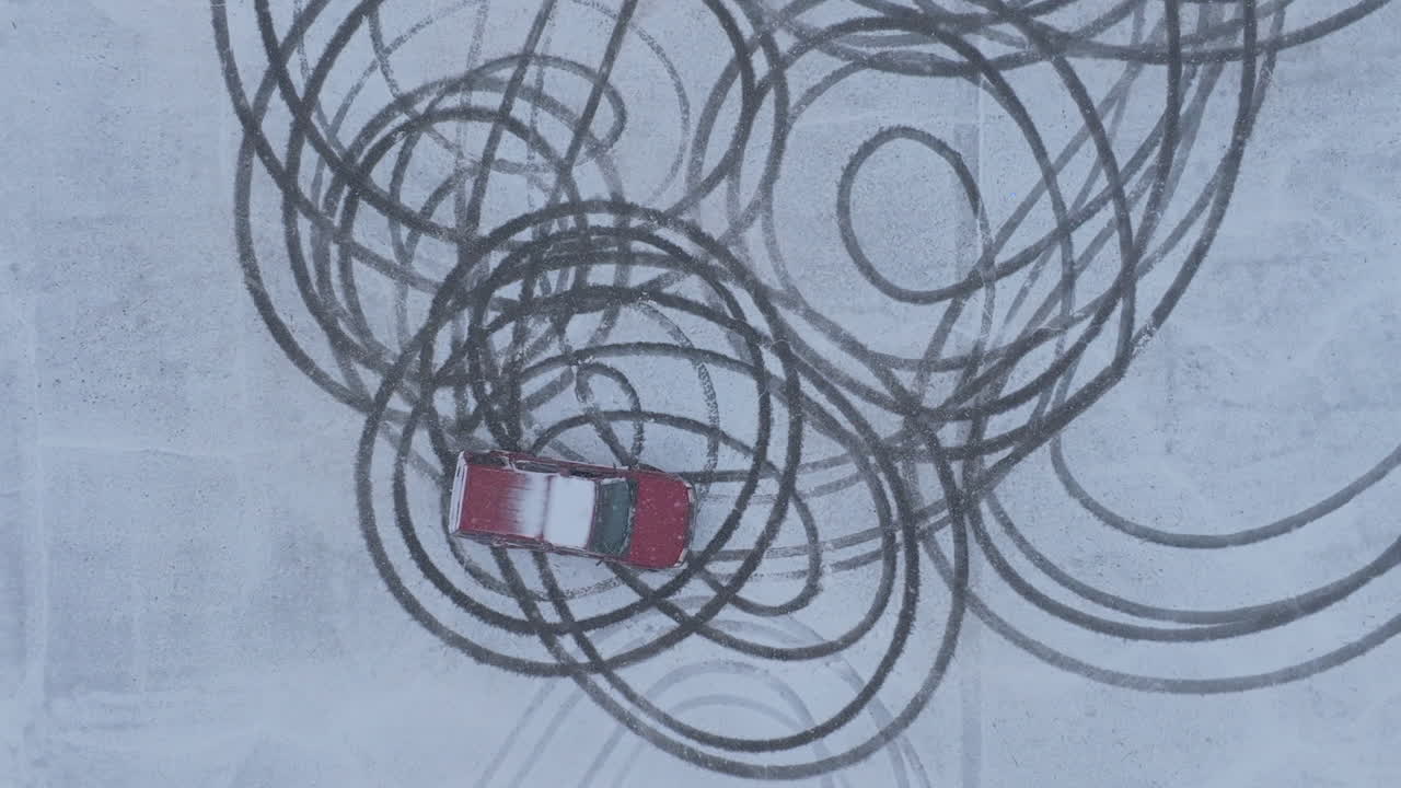 Wider slow motion top down aerial footage of a suv doing donuts in a parking lot covered in snow in Chattanooga, TN.