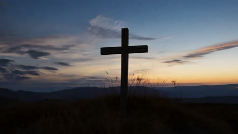 wooden cross stands on a hilltop, silhouetted against a stunning sunset, creating a serene and spiritual atmosphere