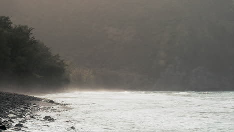 wide shot of waves on black sand beach