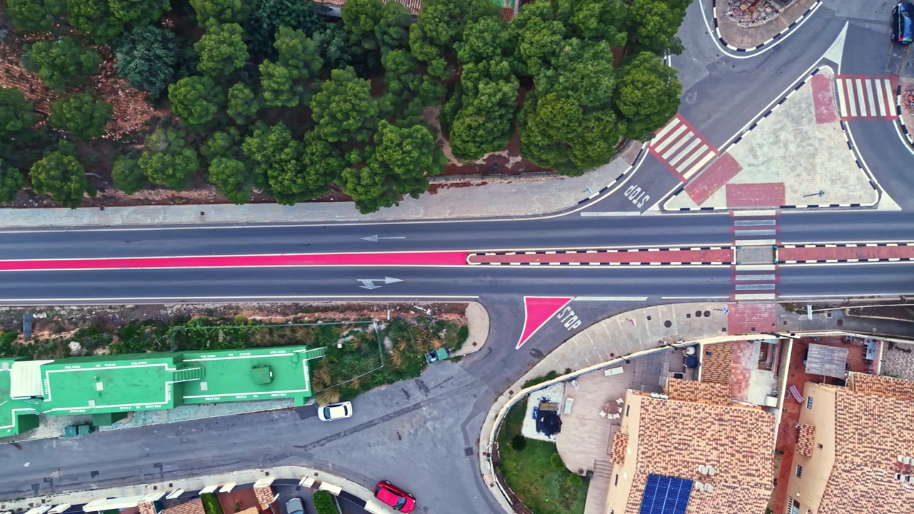 Strada e alberi creano una scena urbana con edifici verdi e auto vicino alla periferia di una città di giorno.