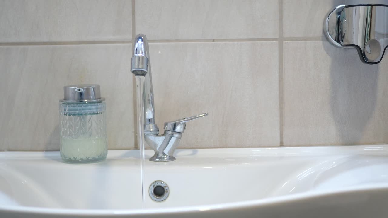 cerca de un fregadero de baño con un grifo de agua corriente
