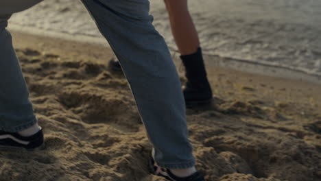 couple feet walking on sandy beach. girl and guy legs going along ocean shore