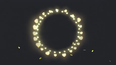 animation of circle of glowing heart christmas fairy lights over gold confetti, on black