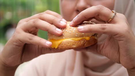 Hand-holding-beef-burger-on-table-close-up