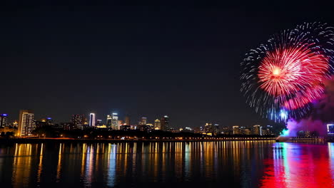 coloridos fuegos artificiales sobre una ciudad junto al río por la noche