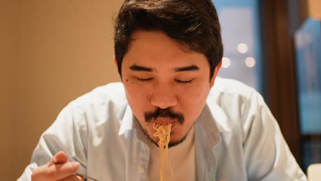 slow motion scene adult middle eastern man eat noodle ramen with happy feeling in the kitchen home for lifestyle concept