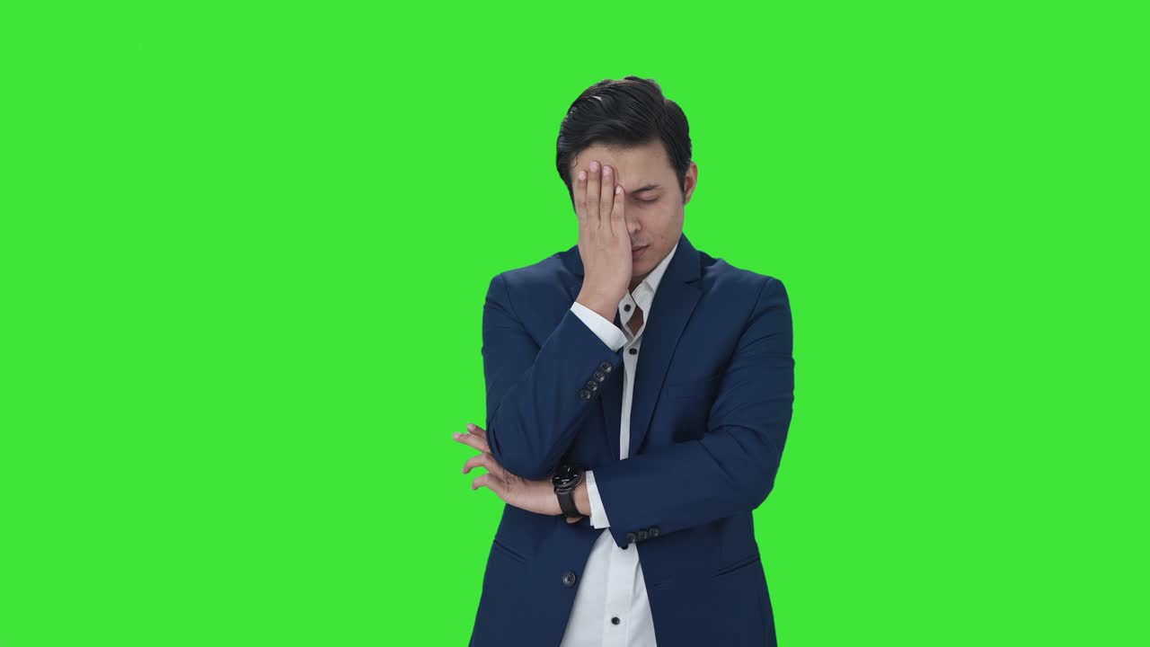 화가 난 인도 사업가 가 머리 를 녹색 스크린 으로 치고 있다