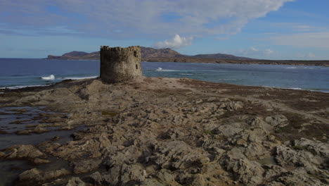 vista aérea en órbita y a baja altitud sobre la torre ubicada en la isola della pelosa, cerdeña en un día soleado