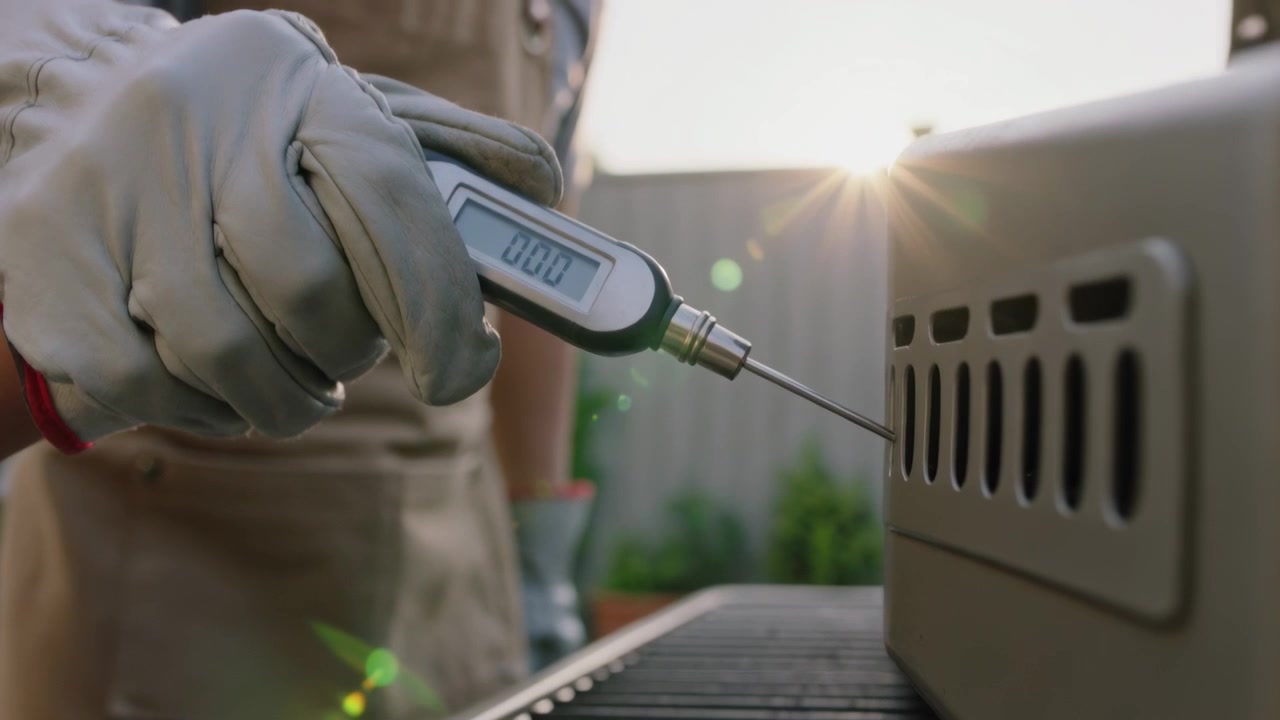 Placing gloved digital probe, adult in beige apron showing grill temperature on patio to child