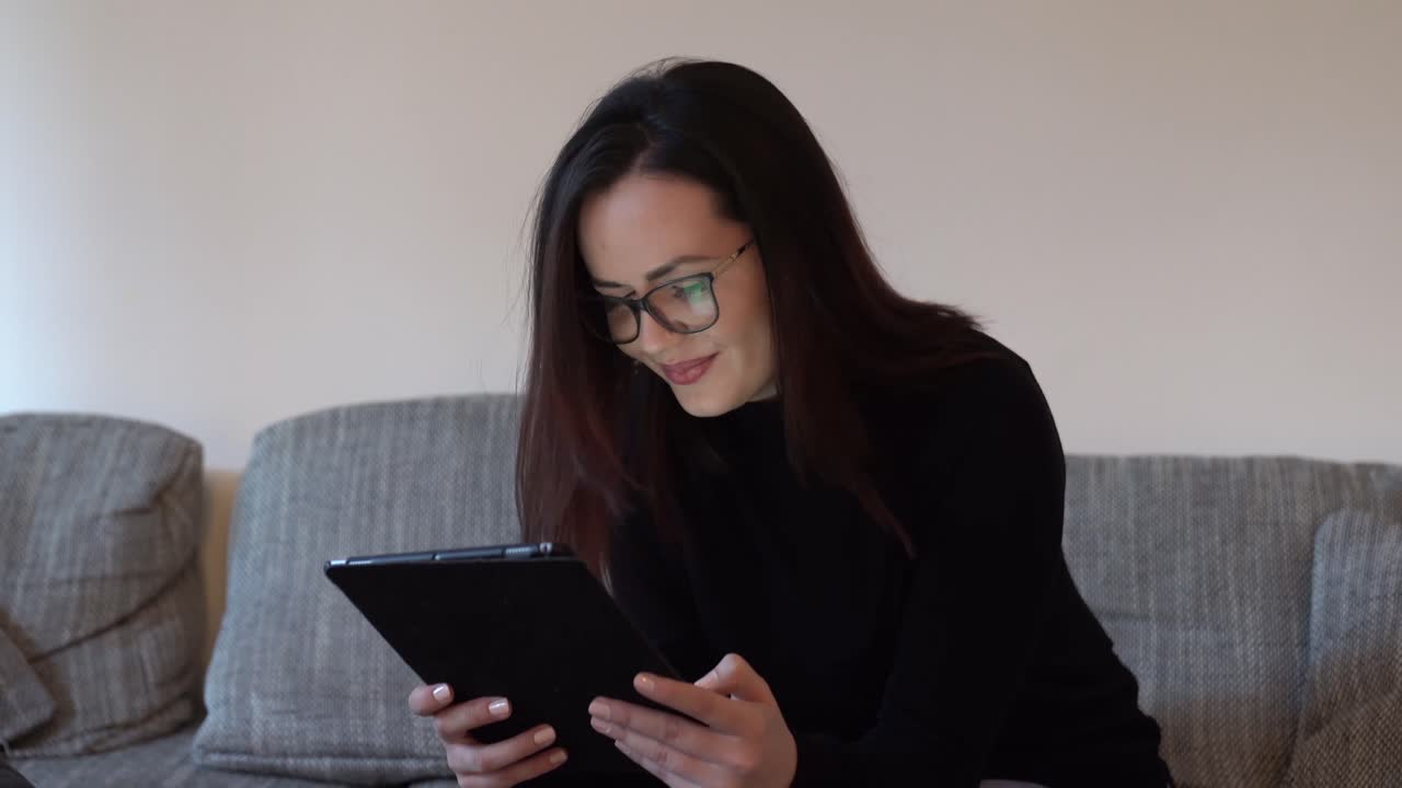 Beautiful young woman having fun while using the tablet in the living room