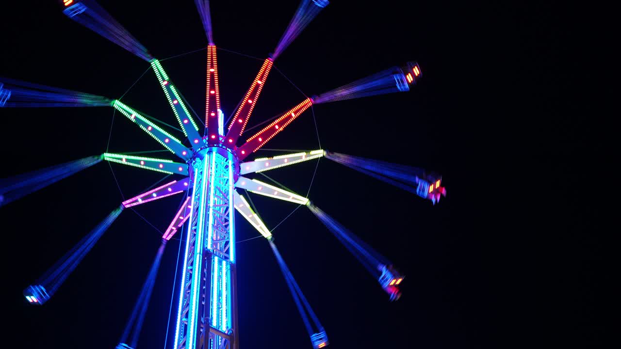 un carrusel iluminado de 4k girando en el cielo oscuro en un parque de atracciones