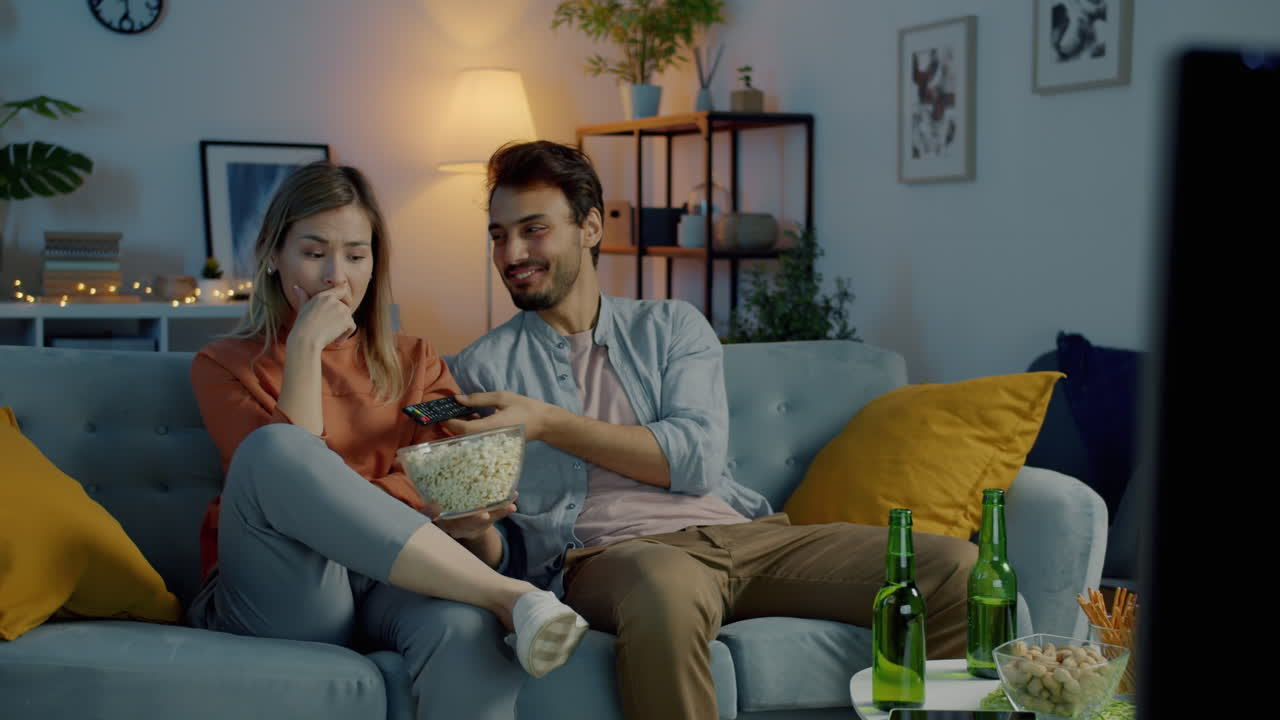 una pareja relajándose en casa viendo la televisión.