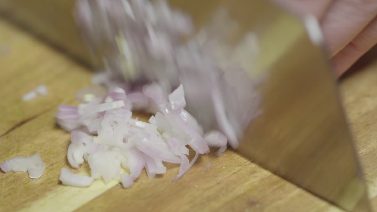 Chopping shallots with a knife on a cutting board