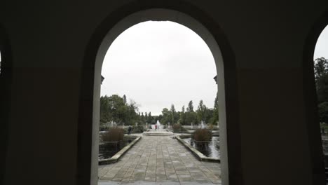 view of a park's pathway with fountain from an arched walkway