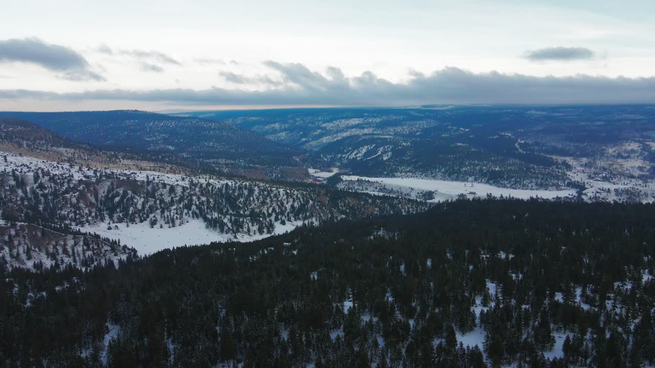 una impresionante toma aérea de los bosques que rodean a clinton, bc, canadá, mirando hacia el valle donde se encuentra el área de descanso del gran bar en la autopista 1 de cariboo, rodeada de montañas cubiertas de nieve