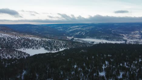 A-stunning-aerial-shot-of-the-forests-surrounding-Clinton,-BC,-Canada,-looking-down-into-the-valley-where-the-Big-Bar-Rest-Area-is-located-on-the-Cariboo-Highway-1,-surrounded-by-snow-capped-mountains