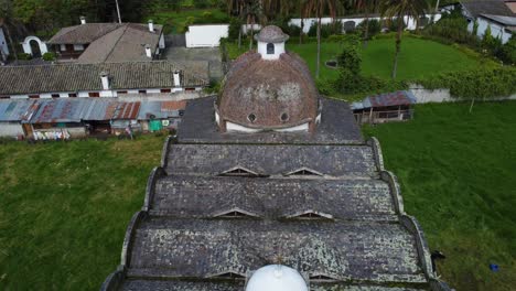 Shot-of-the-Barrio-Güitig-church-with-drone-descending-the-front-facade,-with-some-bees-crossing-in-front-of-the-camera