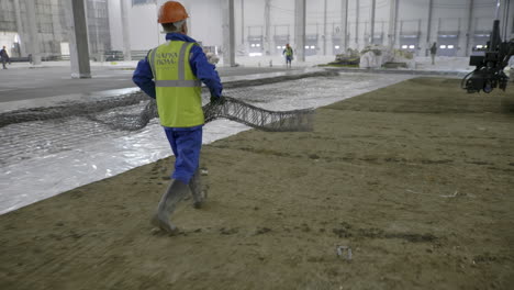 construction workers laying reinforcement for concrete floor in a factory