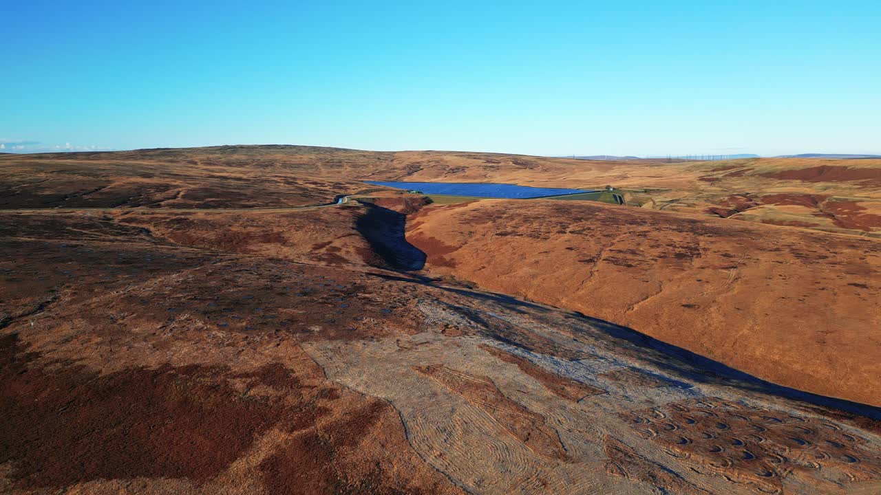 imágenes aéreas de invierno sobrevolando páramos dorados salpicados de escarcha directamente hacia un lago, embalse en la distancia